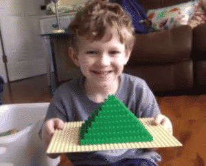 Screenshot of student smiling student showing his pyramid during online LEGO class